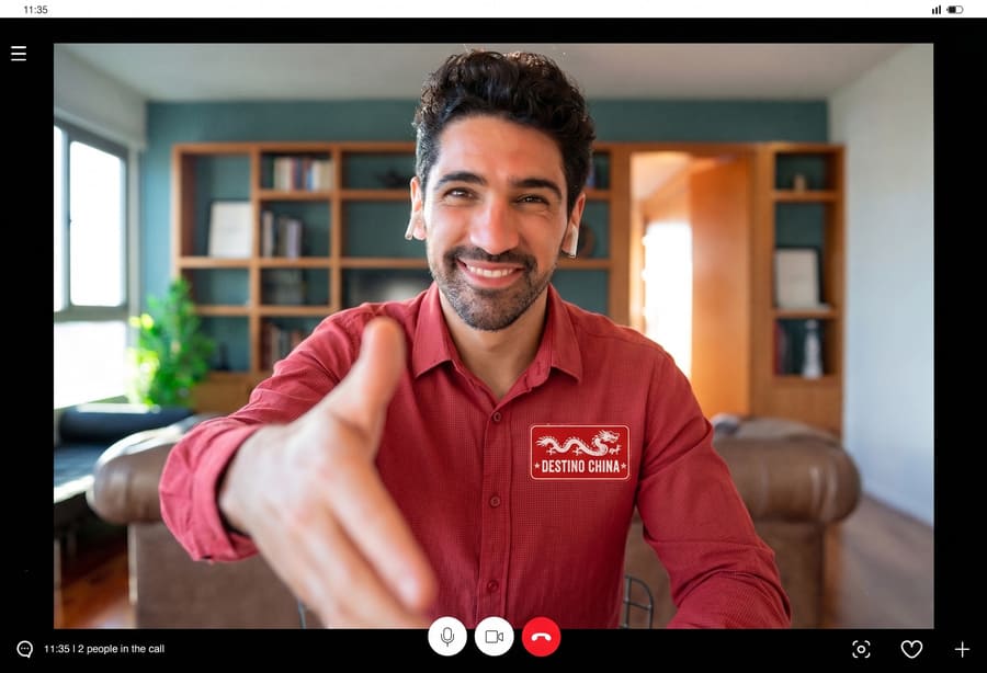Agente de viajes de destino china recibiendo en la recepción a un cliente con la mano extendida y una gran sonrisa